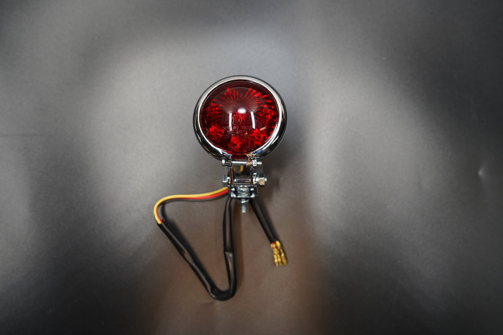 Front main view of vintage-style round LED tail light — domed red lens with matte black metal housing.
