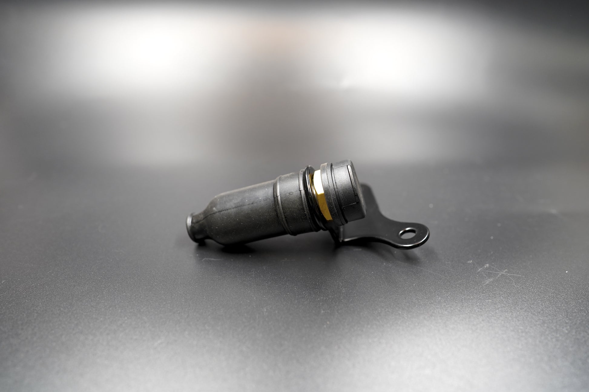 Auxiliary 12V power socket for Triumph Scrambler, laid flat on matte background