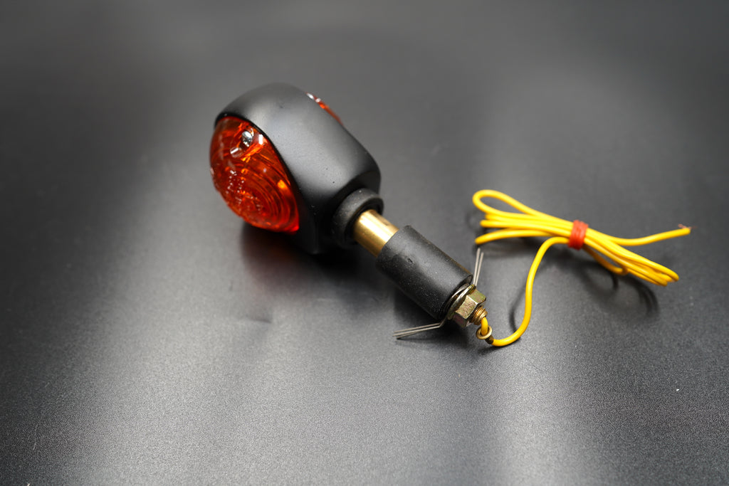 Close-up of amber lens texture and yellow wiring detail — crafted for café racer aesthetics.