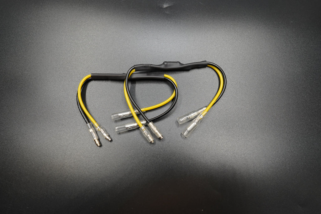 Pair of CANBUS resistors with black and yellow wiring for Triumph LED turn signal upgrades, displayed on metallic background