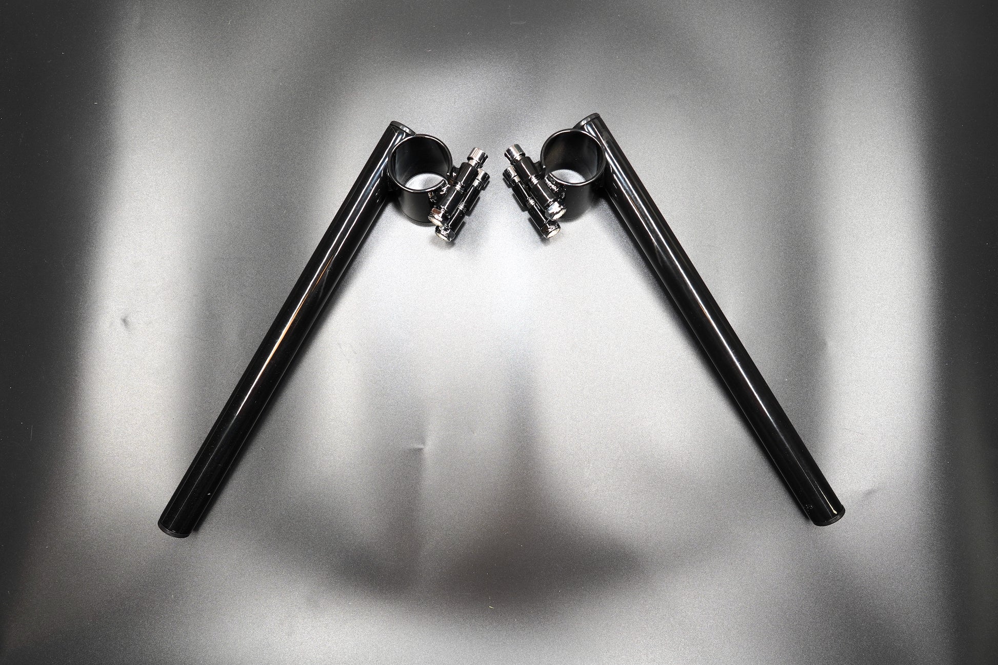 Pair of CNC-machined motorcycle clip-on handlebars with matte black finish, front angle view