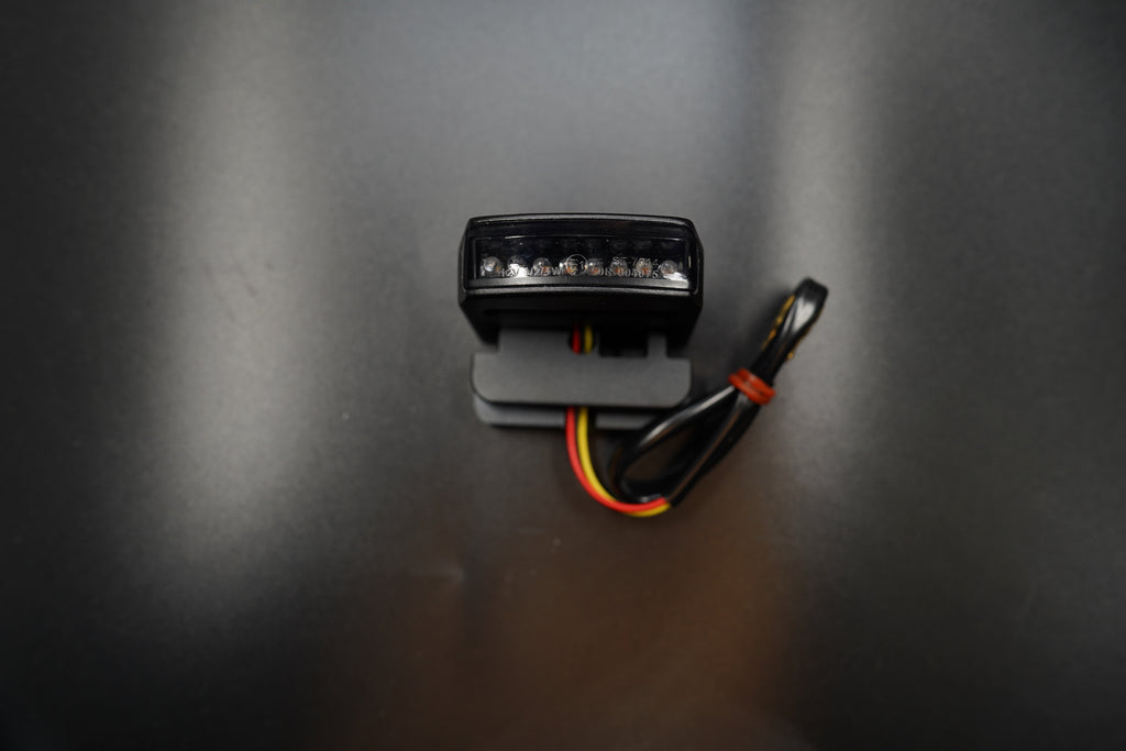 Flat lay composition showing tail light body and wiring on matte background.