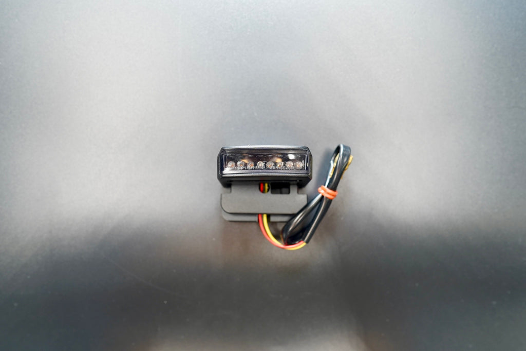 Front angled view of custom LED motorcycle tail light with smoked lens and black anodized aluminum housing.