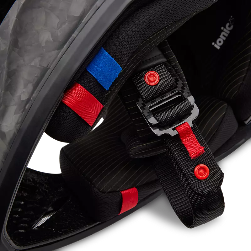Close-up of Fox V3 RS Carbon Helmet titanium D-ring buckle — secure and lightweight fastening system.