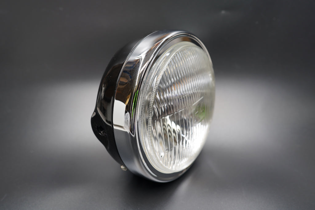 Front angled view of 180mm classic motorcycle headlight with chrome housing and brushed trim ring.