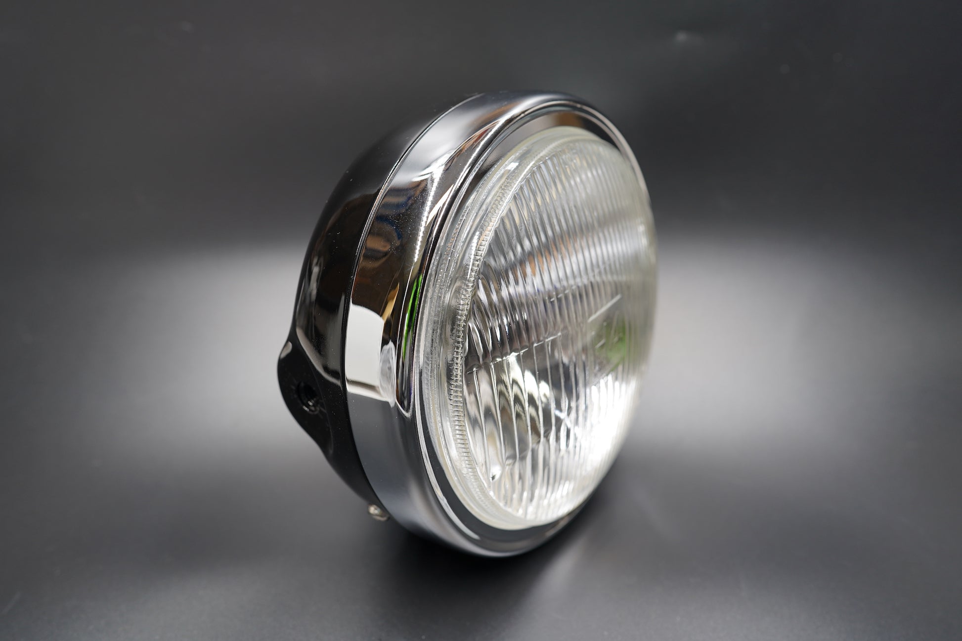 Front angled view of 180mm classic motorcycle headlight with chrome housing and brushed trim ring.