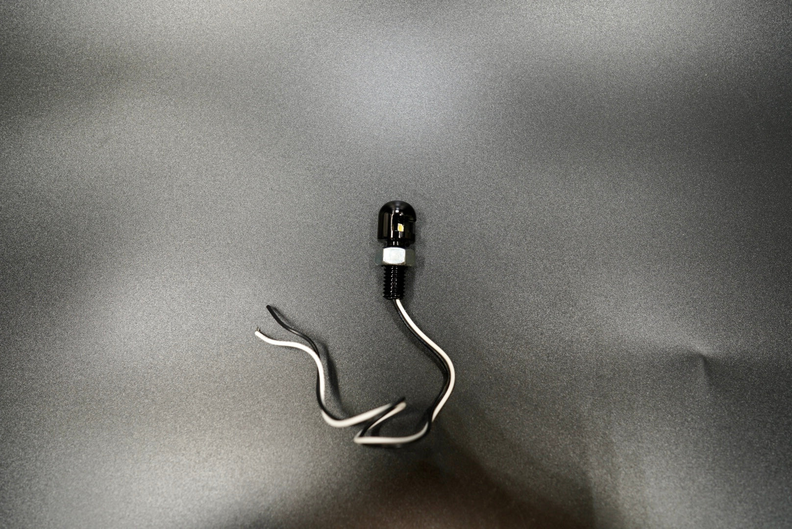 Compact Eagle Eye LED motorcycle license plate lamp with minimalist black aluminum body and white wire leads.