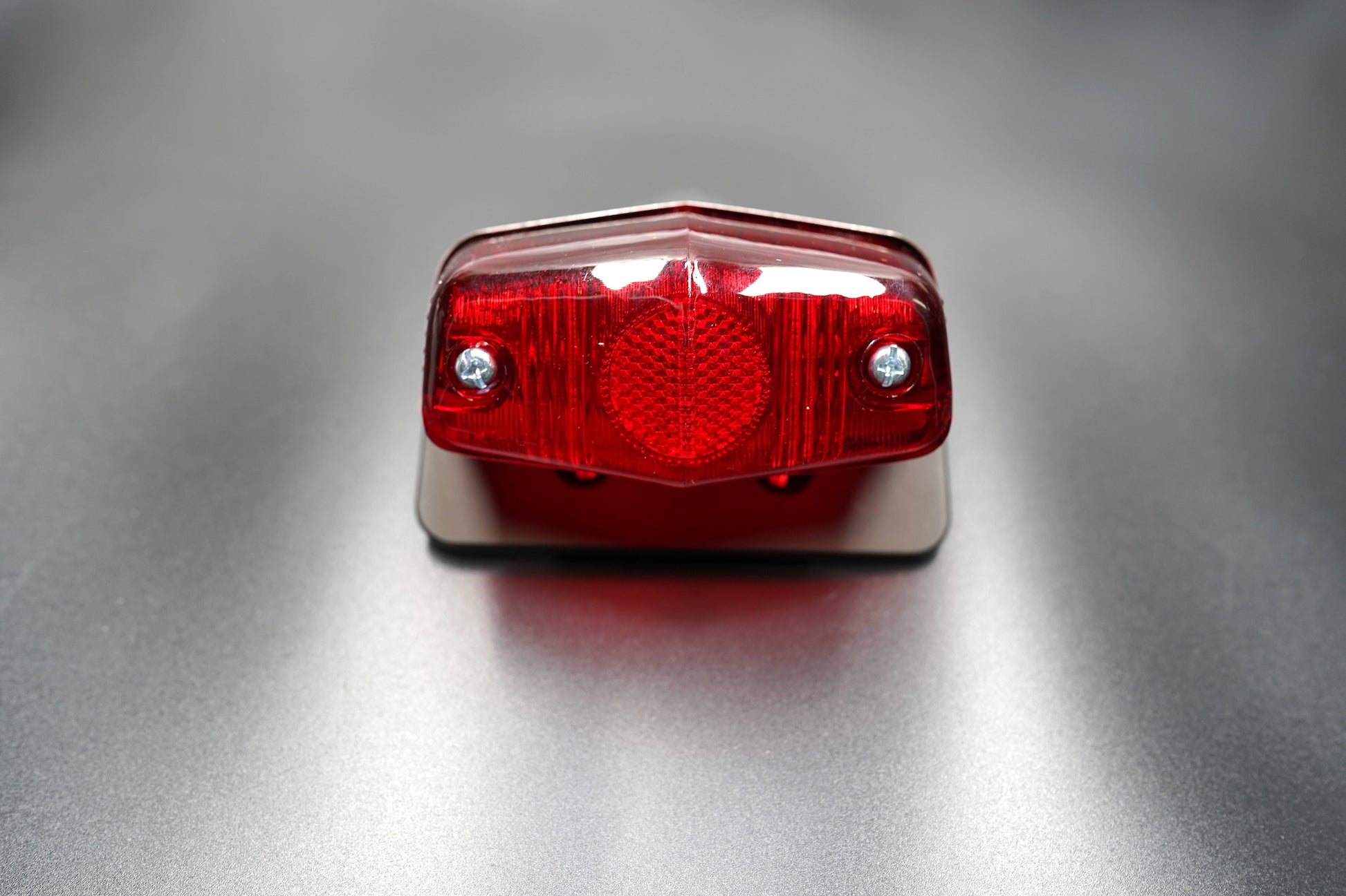 Front main view of Lucas 564-style vintage tail light — red lens with matte black body and polished trim.