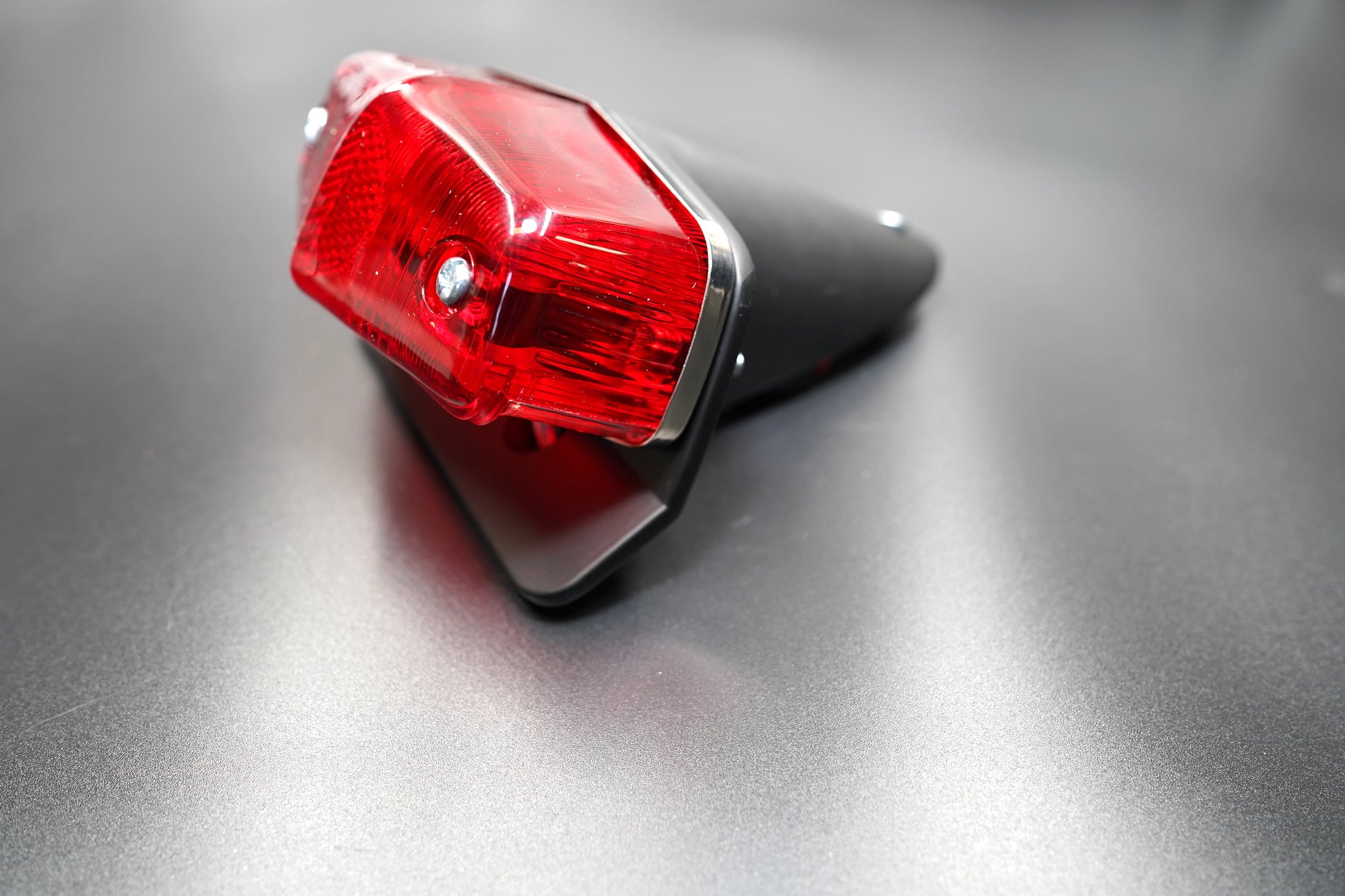 Close-up of red lens and polished silver detailing — timeless British vintage styling for Triumph and BSA builds.