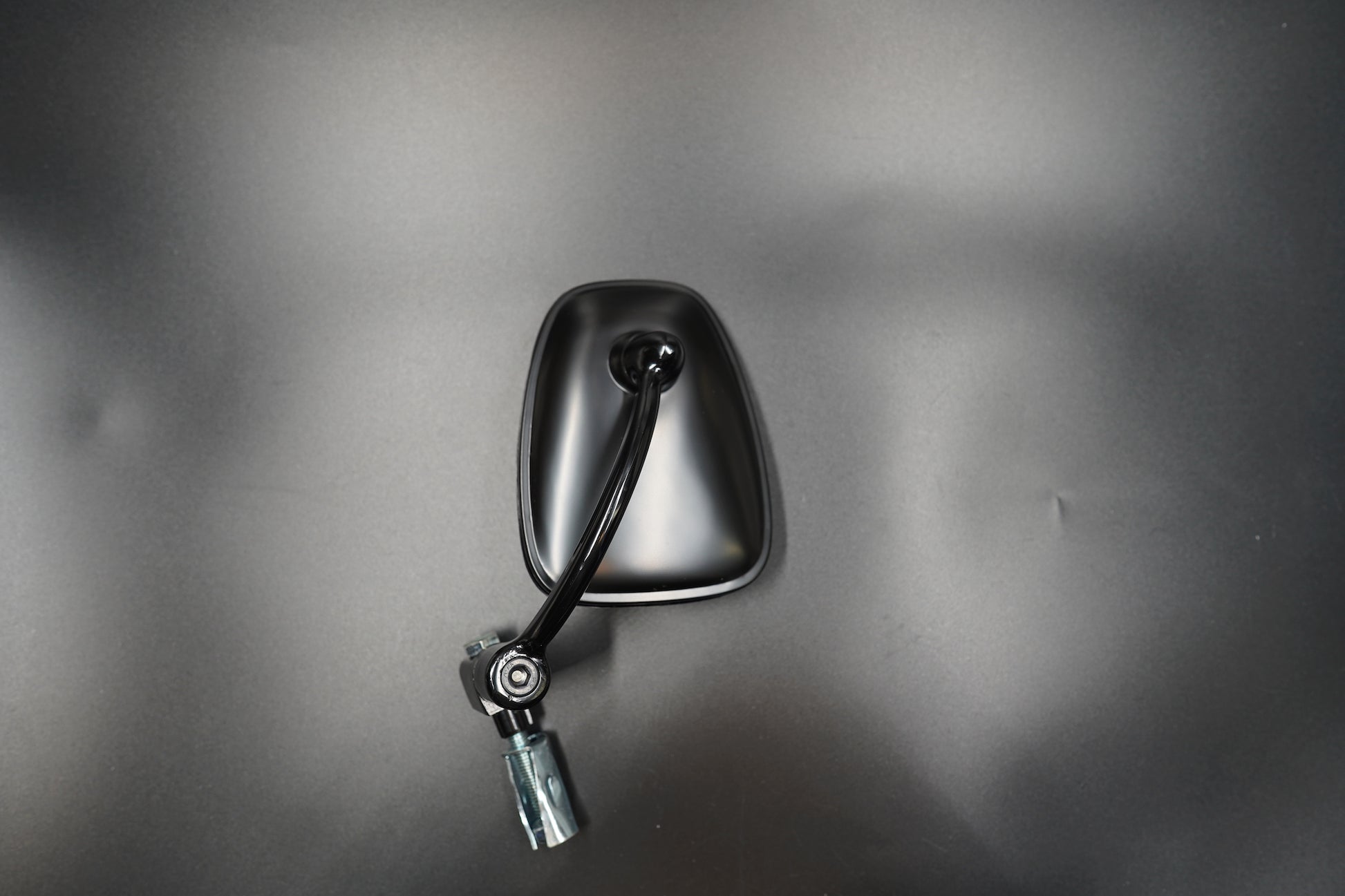 Flat lay of single mirror and mounting hardware on matte background.