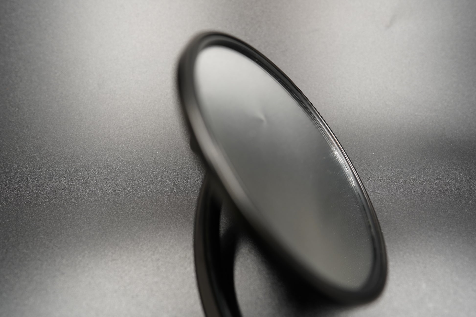 Angled view showing oval mirror shape and minimalist design.