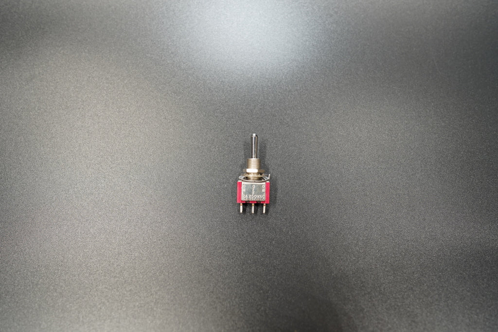 Metal toggle switch front view showing compact red safety cover
