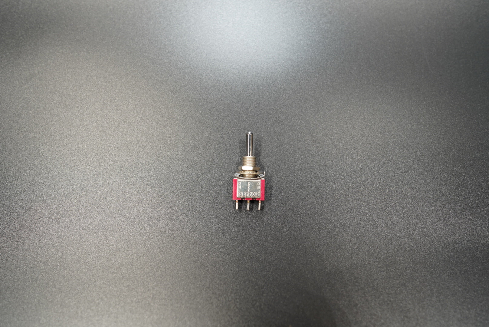 Metal toggle switch front view showing compact red safety cover