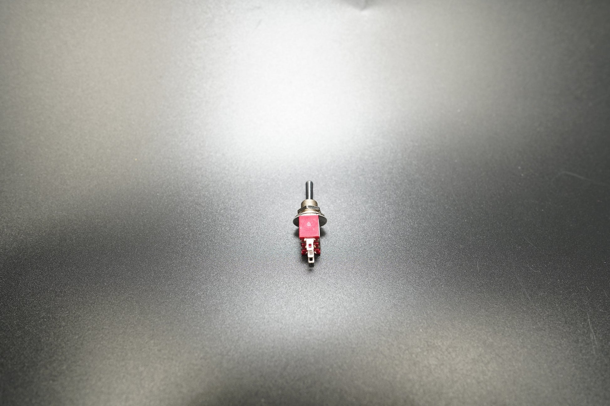 Side profile of ON-OFF-ON metal toggle switch on matte surface