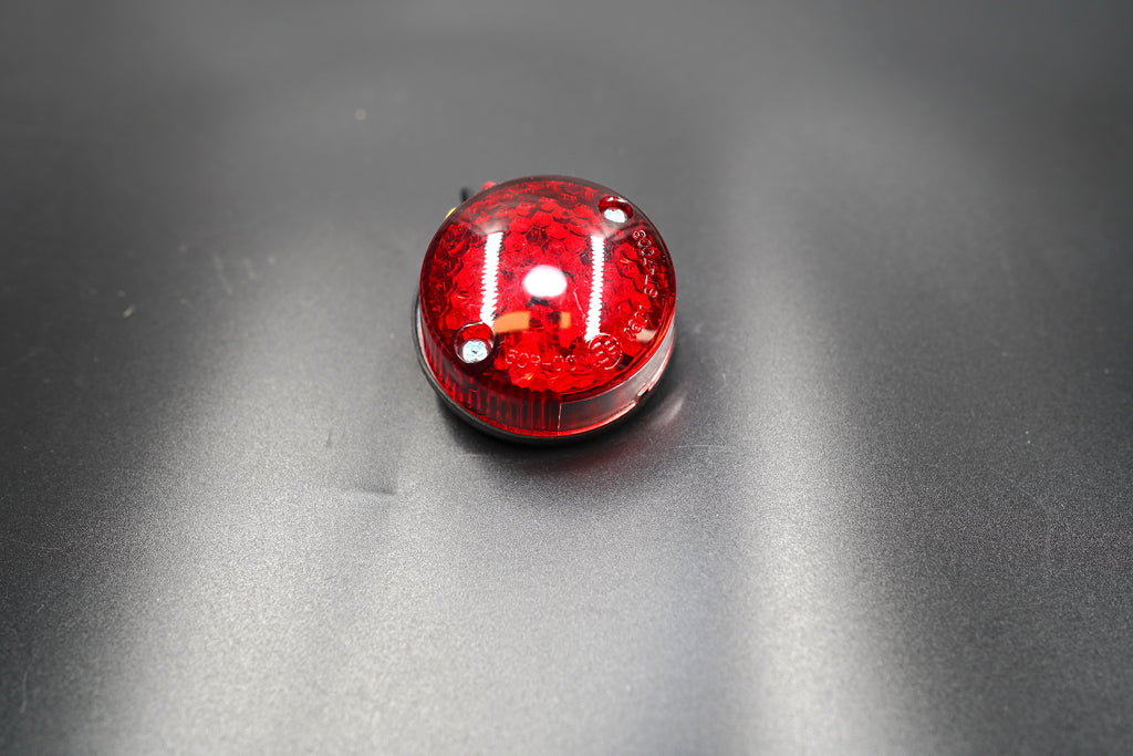 Front main view of minimalist round LED tail light — compact red lens design for café racers and custom bikes.