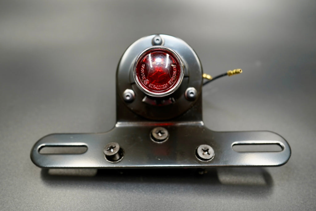 Front view of Old School Type 4 LED tail light with black housing and metal plate bracket — classic British-inspired design.