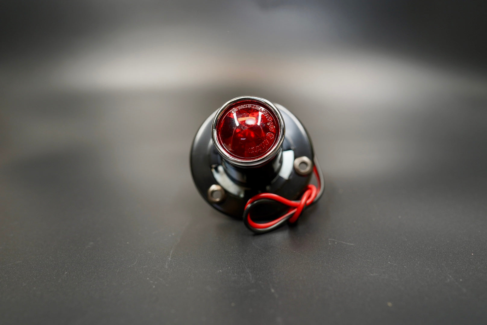 Top view showing red glass lens and matte black steel body with wiring outlet.
