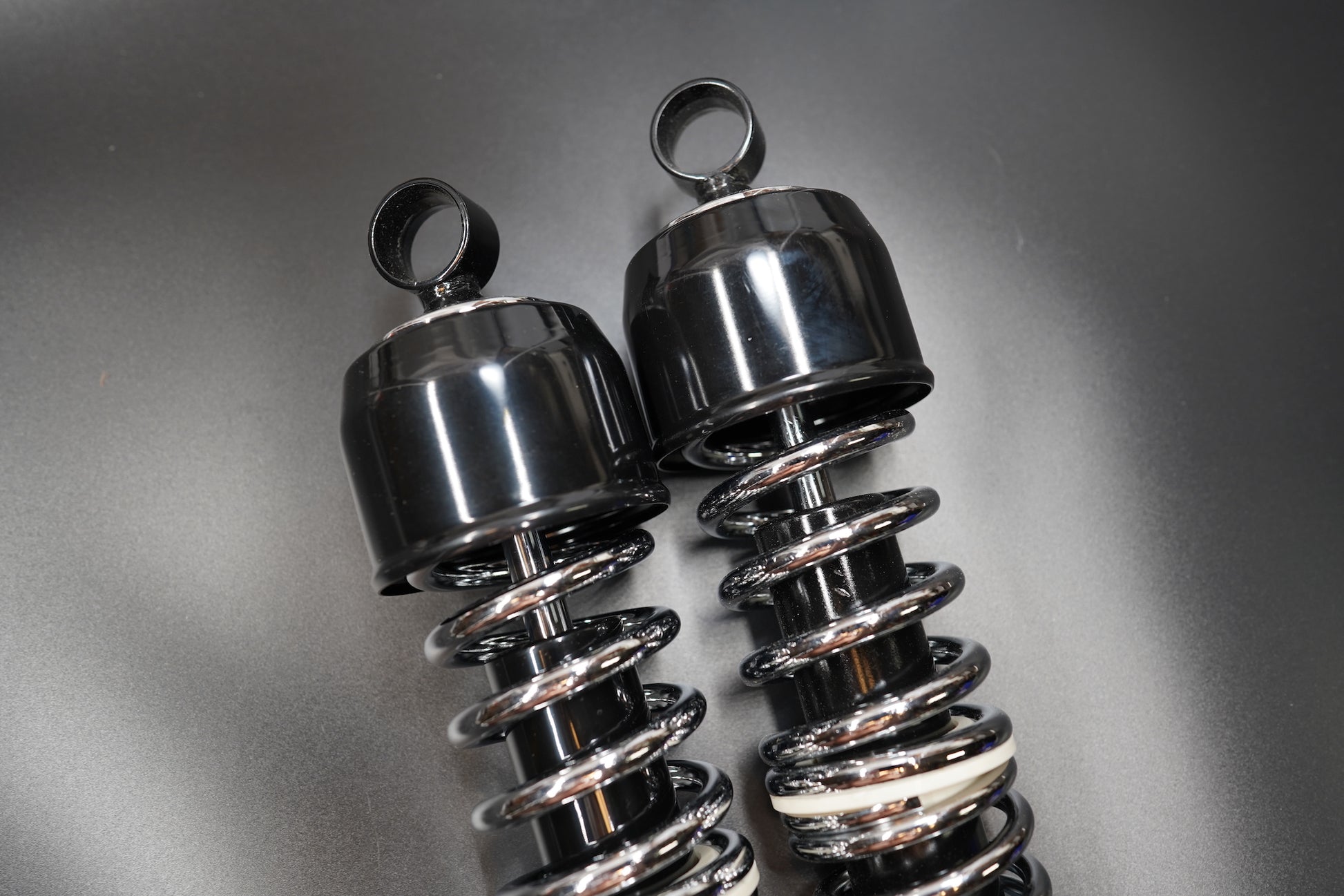 Bottom view focusing on the mounting eyes and chrome spring reflection.