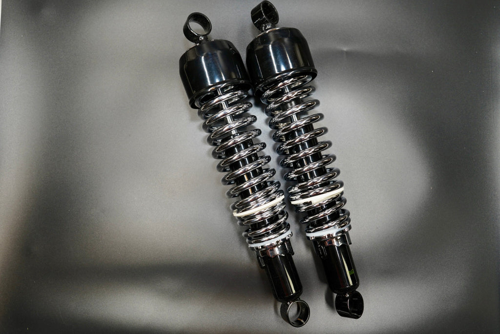 Pair of classic 310mm motorcycle rear shock absorbers with black body and silver springs, front angle view.