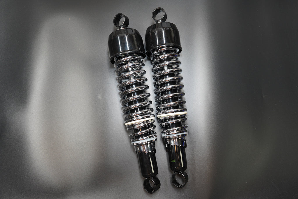 Side view of twin motorcycle shocks showing coiled spring detail and steel mounting eyes.