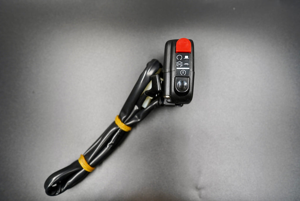 Retro motorcycle handlebar switch assembly with black housing and red button, shown in angled main view.
