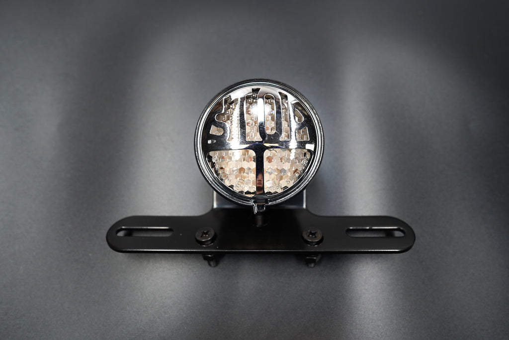 Front view of retro STOP LED motorcycle tail light with chrome faceplate and black license plate bracket.