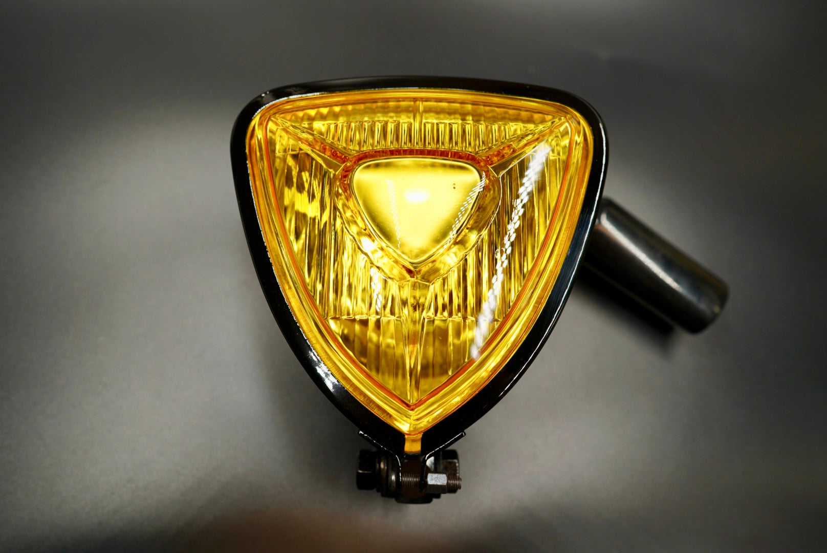 Front view of retro triangle motorcycle headlight with amber lens and chrome trim — classic meets modern.