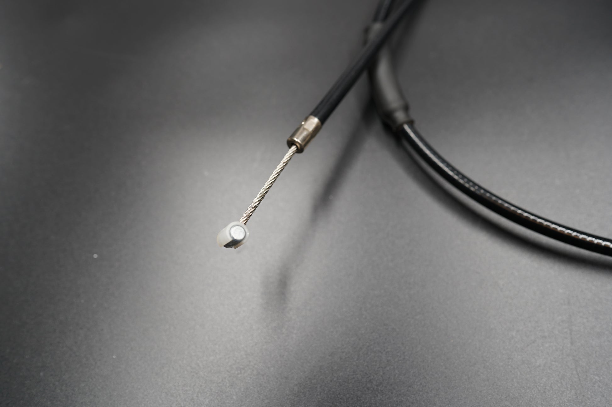 Close-up of Triumph T120/T100 extended clutch cable tip and sheath on matte surface