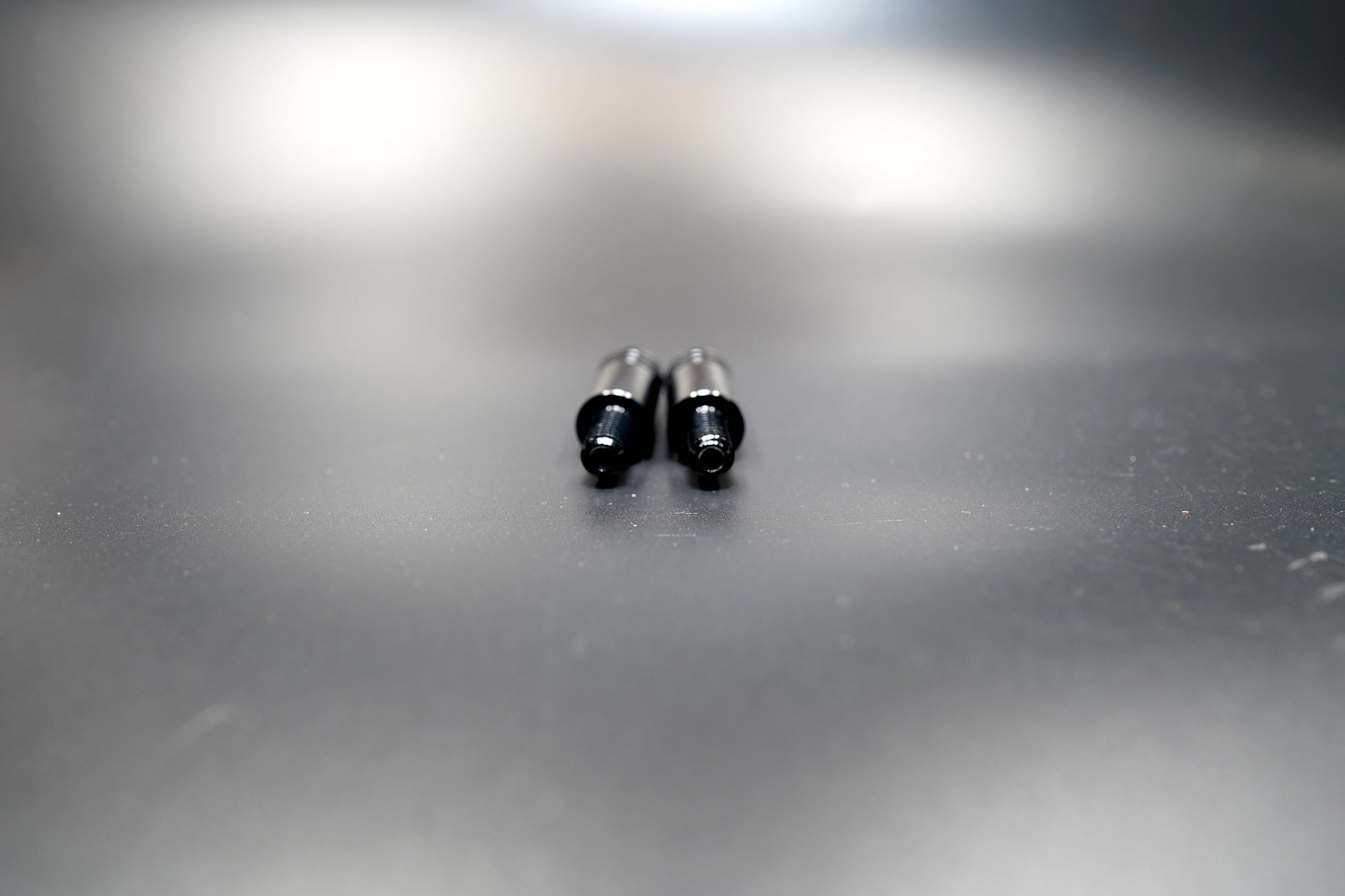 Side view of Triumph turn signal extension rods showing threaded ends and smooth matte finish