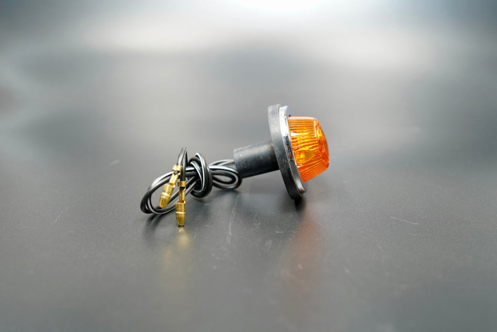 Main front view of universal amber halogen turn signal light — compact 12V indicator with chrome ring and black housing.