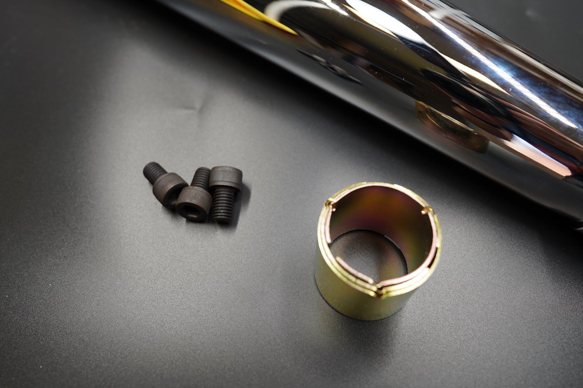 Bracket, clamp, and reducer sleeve displayed next to silencer