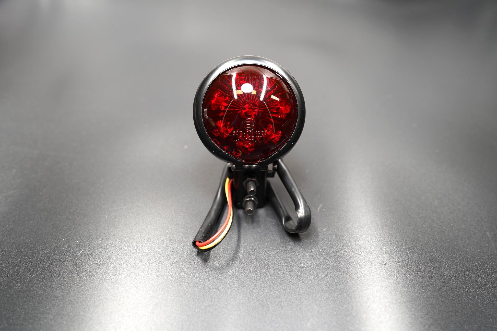 Front main view of vintage-style round LED tail light — domed red lens with matte black metal housing.