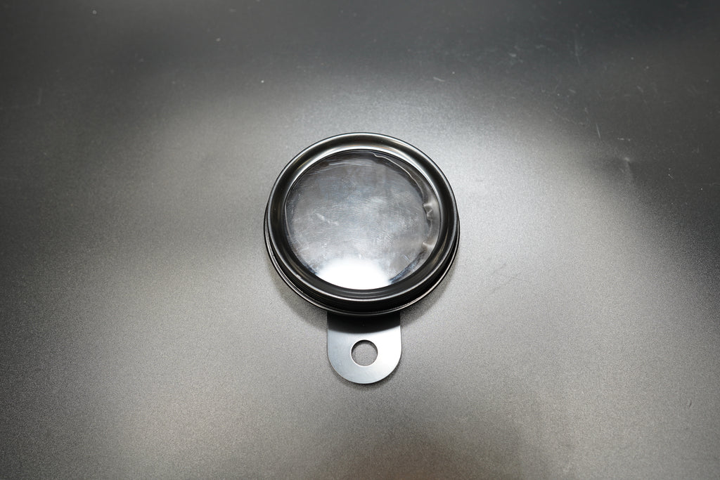 Vintage round motorcycle number plate front view showing brushed metal surface and mounting tab