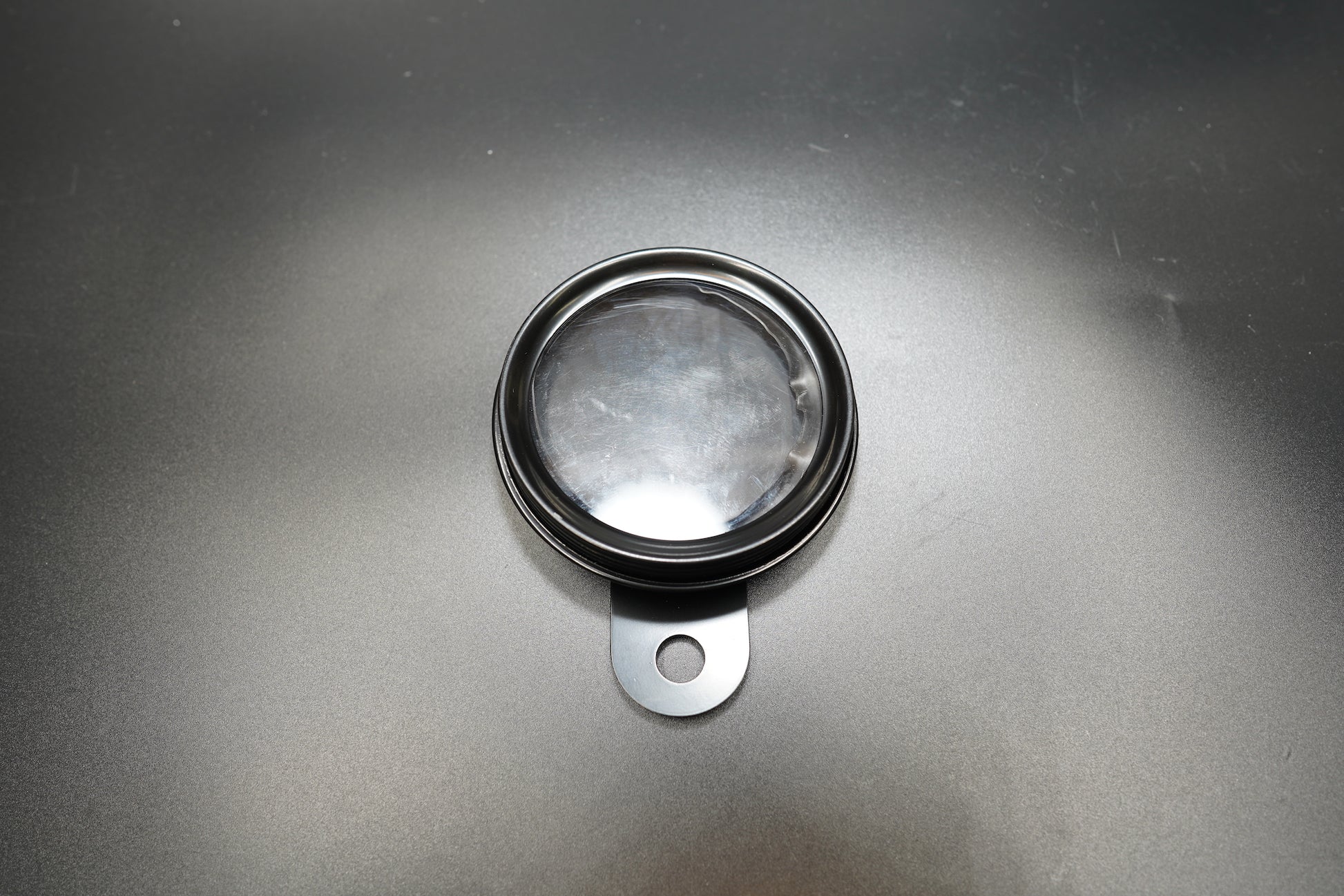 Vintage round motorcycle number plate front view showing brushed metal surface and mounting tab